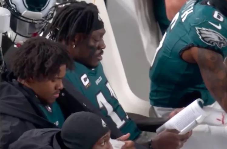 NFL Player Reads on Sideline During Playoff Game